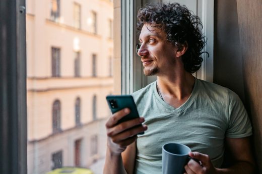 Image depicting the Regulatory Affairs Academy: a man gazing out of a window while holding a phone, evoking a calm and reflective atmosphere.